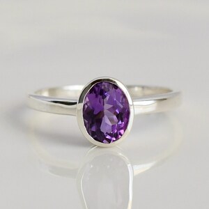 May include: A silver ring with a purple amethyst gemstone.