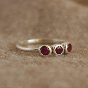 Peut inclure: Une bague en argent avec quatre pierres pr&eacute;cieuses rouges dispos&eacute;es en rang&eacute;e.