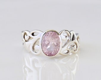 May include: A silver ring featuring a delicate floral design and a pink oval gemstone.