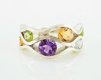May include: A silver ring with a wavy design featuring five gemstones: amethyst, peridot, citrine, and two white topaz.