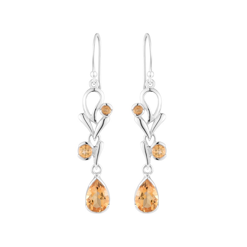 May include: Silver dangle earrings with a floral design and teardrop-shaped topaz gemstones.