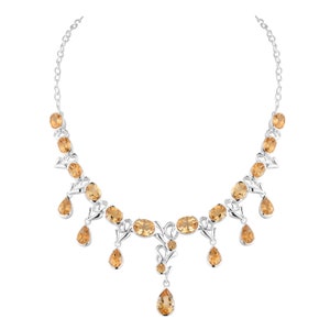 May include: A silver necklace with a delicate design features multiple teardrop-shaped and oval-shaped topaz gemstones in a warm amber color.