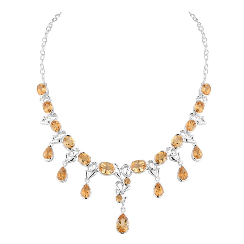May include: A silver necklace with a delicate design features multiple teardrop-shaped and oval-shaped topaz gemstones in a warm amber color.