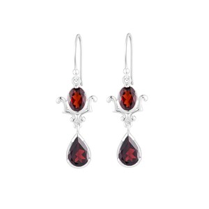 Puede incluir: Pendientes de plata con dos piedras de granate rojo. La piedra superior es de forma ovalada y la piedra inferior es de forma de l&aacute;grima.