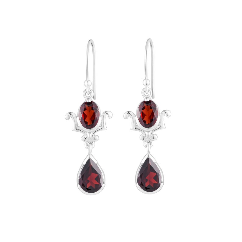 Puede incluir: Pendientes de plata con dos piedras de granate rojo. La piedra superior es de forma ovalada y la piedra inferior es de forma de l&aacute;grima.