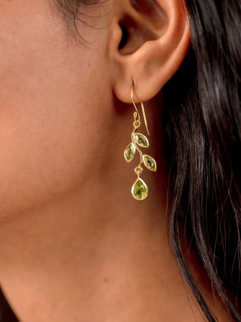 Gold leaf earrings featuring marquise leaves and a pear-cut peridot drop. Crafted from 24k gold vermeil over 925 sterling silver, these earrings are inspired by nature, highlighting the vibrant green. Also available with a matching necklace and ring.
