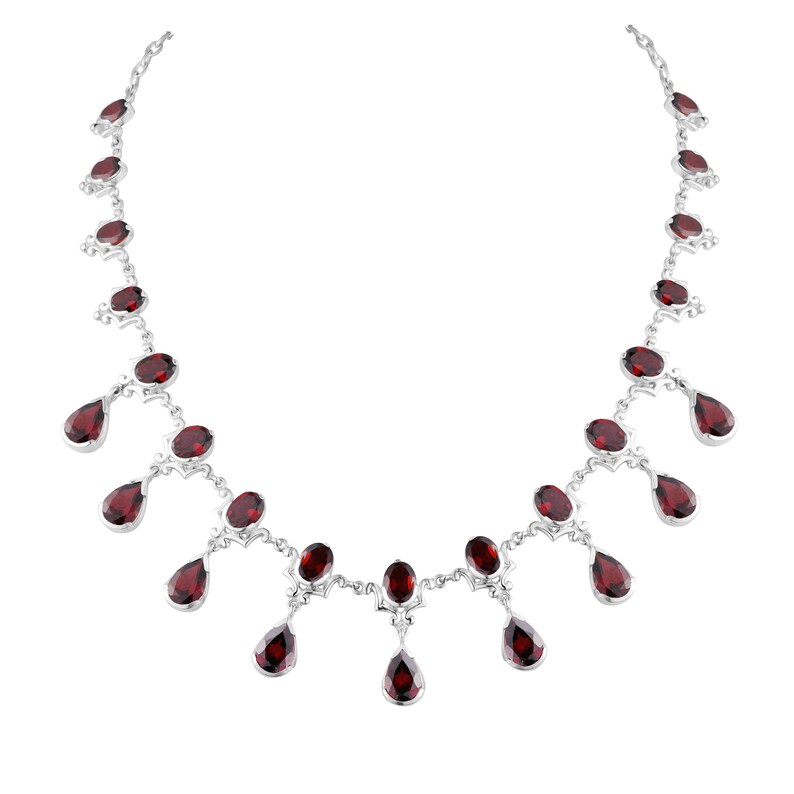Puede incluir: Un collar de plata con un dise&ntilde;o delicado presenta una fila de gotas de piedras preciosas rojas colgantes. El collar est&aacute; adornado con m&uacute;ltiples piedras preciosas rojas de forma ovalada.