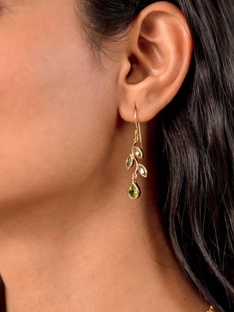 Gold leaf earrings featuring marquise leaves and a pear-cut peridot drop. Crafted from 24k gold vermeil over 925 sterling silver, these earrings are inspired by nature, highlighting the vibrant green. Also available with a matching necklace and ring.