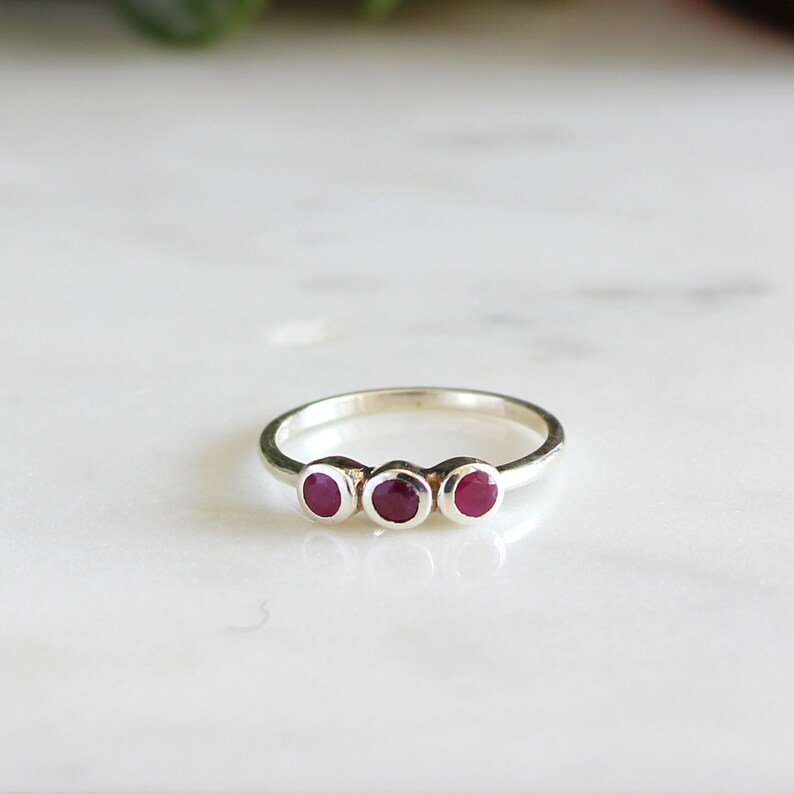 Peut inclure: Une bague en argent avec trois pierres rondes rouges.