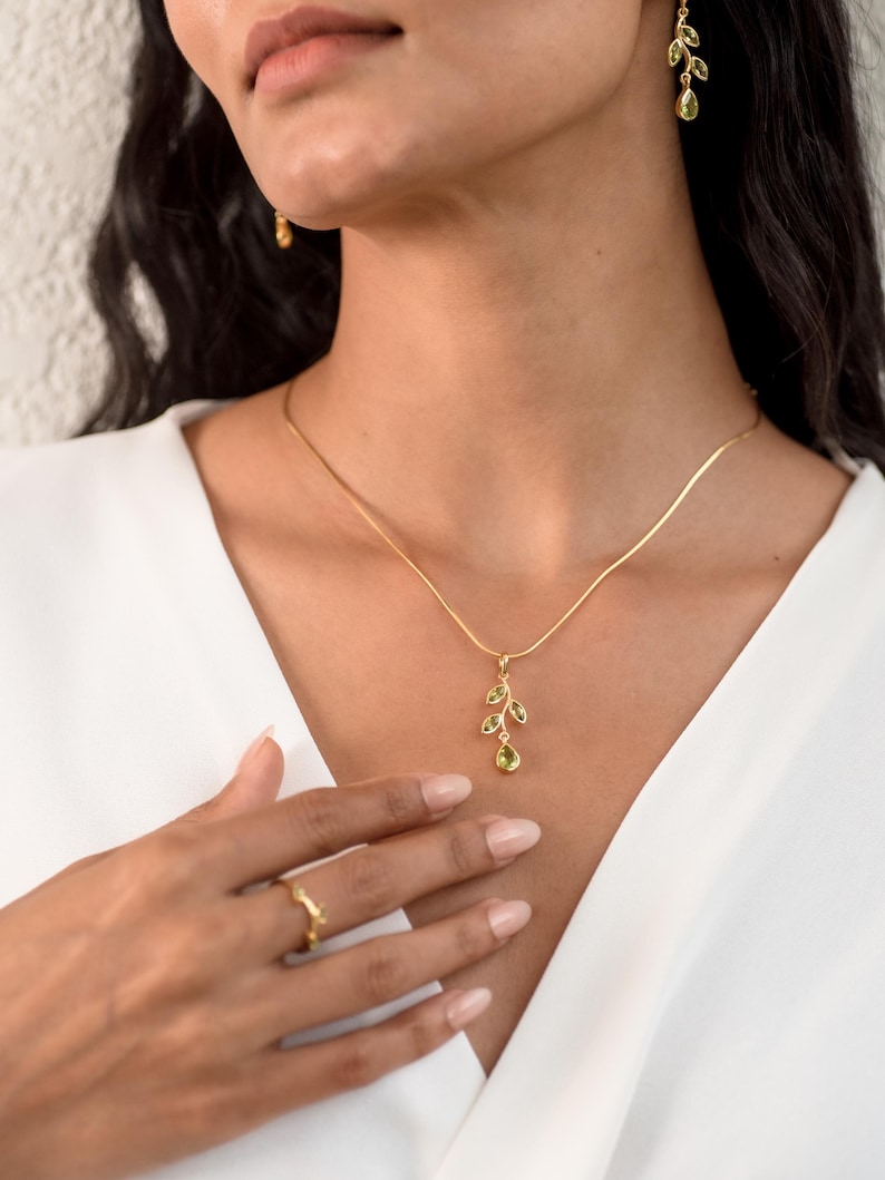Gold leaf earrings featuring marquise leaves and a pear-cut peridot drop. Crafted from 24k gold vermeil over 925 sterling silver, these earrings are inspired by nature, highlighting the vibrant green. Also available with a matching necklace and ring.