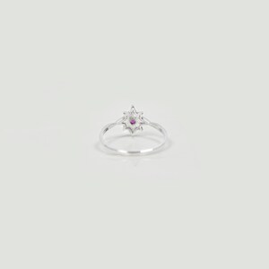 Op de afbeelding: Een zilveren ring met een stervormig ontwerp met een klein roze edelsteentje in het midden.