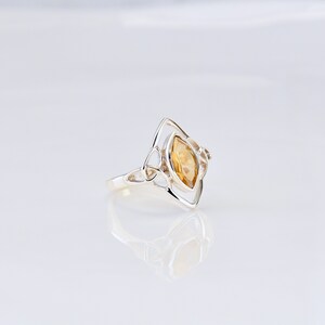 May include: A silver ring with a Celtic knot design and a yellow topaz gemstone.