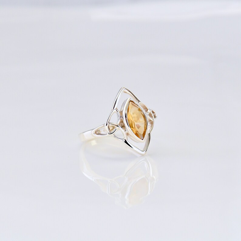 May include: A silver ring with a Celtic knot design and a yellow topaz gemstone.