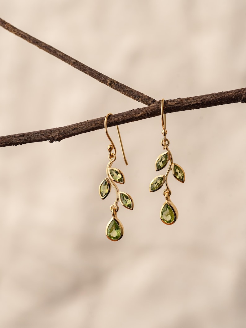 Gold leaf earrings featuring marquise leaves and a pear-cut peridot drop. Crafted from 24k gold vermeil over 925 sterling silver, these earrings are inspired by nature, highlighting the vibrant green. Also available with a matching necklace and ring.