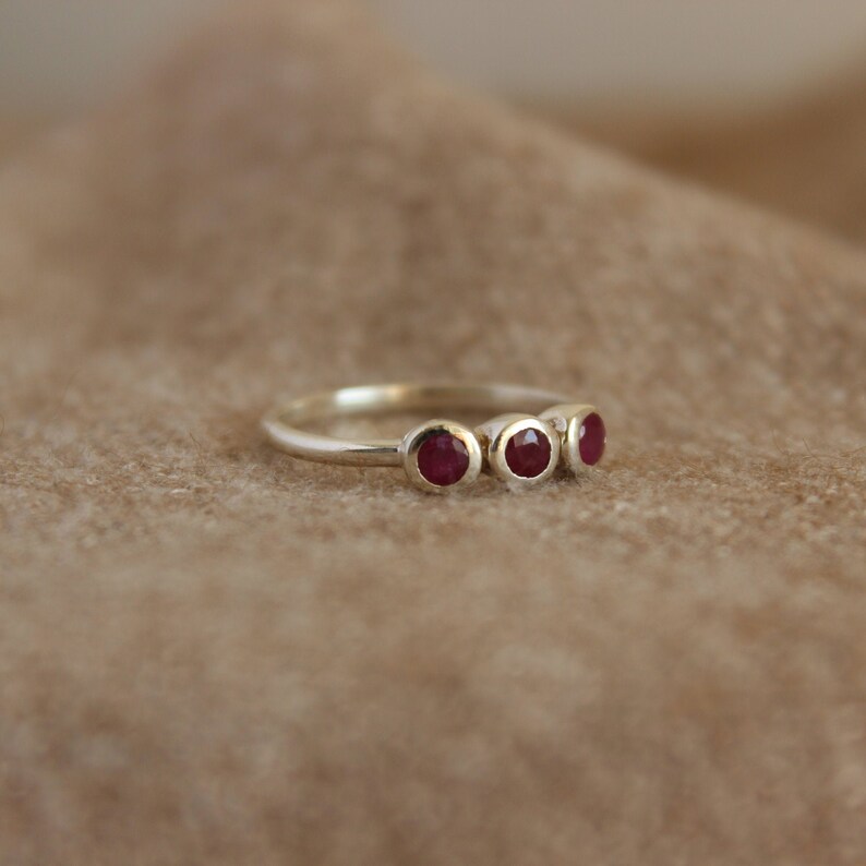 Peut inclure: Une bague en argent avec quatre pierres pr&eacute;cieuses rouges dispos&eacute;es en rang&eacute;e.