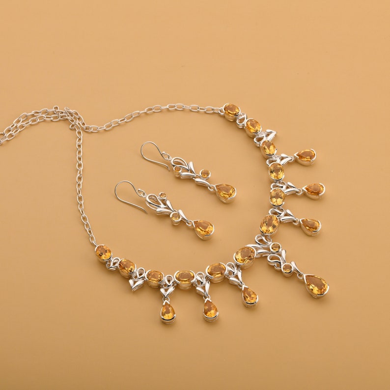 May include: A silver necklace and earrings set with teardrop-shaped topaz gemstones. The necklace has a delicate chain and a pendant with multiple topaz stones. The earrings are dangle style with a single topaz stone.