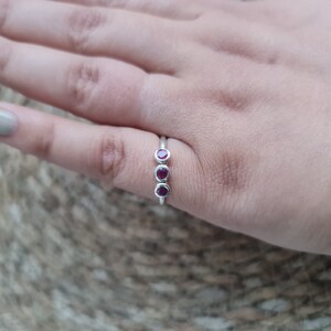 Peut inclure: Une bague en argent avec trois pierres pr&eacute;cieuses rouges dispos&eacute;es en rang&eacute;e.