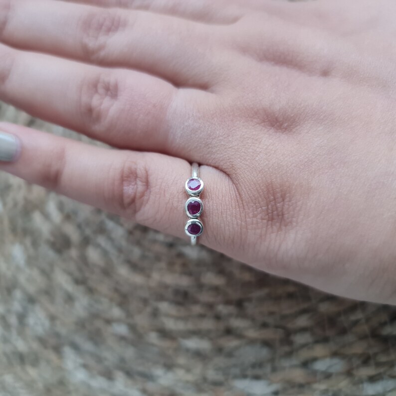 Peut inclure: Une bague en argent avec trois pierres pr&eacute;cieuses rouges dispos&eacute;es en rang&eacute;e.