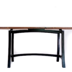 May include: A wooden table with a dark brown top and black legs. The legs are curved and have a unique design.