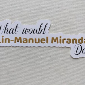 Puede incluir: Pegatina blanca con el texto "What would Lin-Manuel Miranda Do?" en letras negras y doradas.
