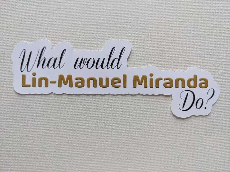 Puede incluir: Pegatina blanca con el texto "What would Lin-Manuel Miranda Do?" en letras negras y doradas.
