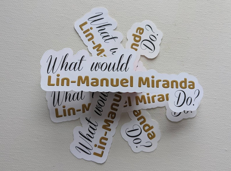 Puede incluir: Un conjunto de pegatinas blancas con letras doradas que dicen "What would Lin-Manuel Miranda Do?" Las pegatinas est&aacute;n dispuestas en c&iacute;rculo.