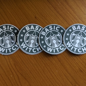 May include: Four round stickers with a black and white design. The stickers feature a witch with a pointed hat and the text "BASIC WITCH" with stars around the text.