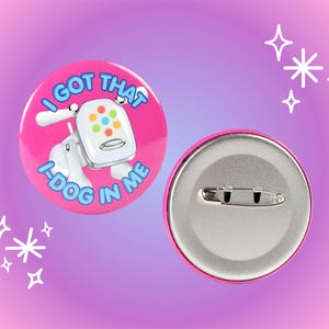 May include: Pink button with a white dog illustration and the text "I got that I-dog in me". The back of the button is silver with a safety pin.