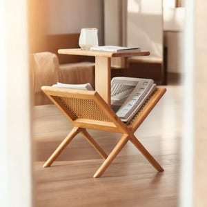May include: A wooden magazine rack with a woven cane panel and a top shelf. The rack is holding several magazines, including one with the word "CEREAL" on the cover.