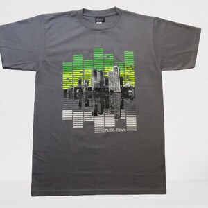 May include: Gray t-shirt with a graphic print of a city skyline with green and yellow sound bars and the text "MUSIC TOWN".