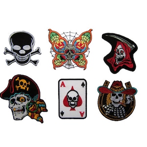 Könnte beinhalten: Sechs gestickte Bügelbilder mit verschiedenen Totenkopfmotiven. Die Patches beinhalten einen Totenkopf mit Knochen, einen Totenkopf mit einem Schmetterling, einen Totenkopf mit einer Sense, einen Totenkopf mit einer Piratenmütze, einen Totenkopf mit einer Spielkarte und einen Totenkopf mit einem Cowboyhut.