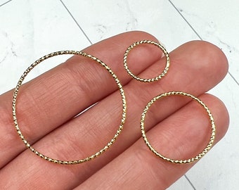 May include: Three gold-toned hoop earrings of different sizes. The hoops are made of a twisted wire design.