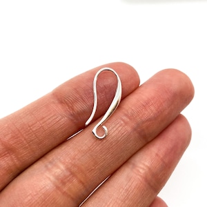 May include: Silver earring hook with a smooth, curved design. The hook is open at the top and has a small loop at the bottom.