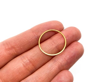 Könnte beinhalten: Ein goldfarbener Metallring, in einer Hand gehalten, mit einer glatten, kreisförmigen Form.