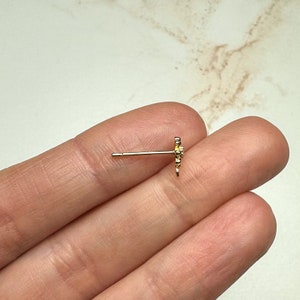 K&ouml;nnte beinhalten: Ein goldfarbener Ohrring mit einem kleinen, zarten Blumenmuster. Der Ohrring ist aus Metall und hat einen Stiftverschluss.