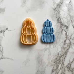 May include: A light blue fondant pumpkin stack cookie cutter and a matching stack of pumpkins made from fondant.