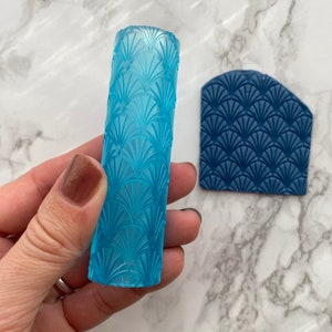 May include: A set of two blue rolling pins for baking, one is a cylinder and the other is a flat rectangle. Both have a decorative fan pattern.