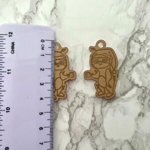 May include: Two wooden ornaments of a sloth wearing a Santa hat and holding a gift. The ornaments are approximately 4 cm tall.
