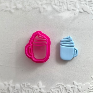 Peut inclure: Deux emportes-pièces, l'un rose et l'autre bleu clair, en forme de tasses avec de la crème fouettée sur le dessus.