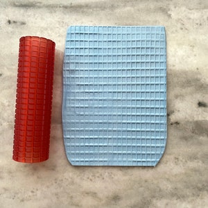 May include: A red rolling pin and a blue textured silicone mat, both with a waffle pattern.
