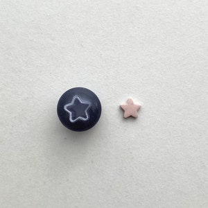 May include: A dark blue button with a white star in the center and a light pink star button.