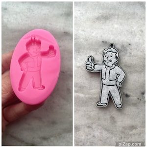 May include: Pink silicone mold with a raised design of a cartoon character giving a thumbs up. The character is wearing a jumpsuit and has a hairstyle similar to the Fallout video game character.