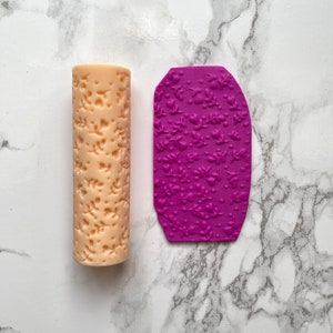 May include: A set of two rolling pins for baking, one is beige and the other is purple. Both have a floral design.