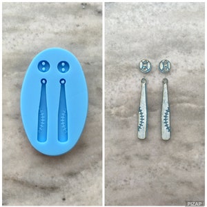 May include: A blue silicone mould for making baseball bat earrings. The mould has two cavities for the earrings and two smaller cavities for the baseballs. The mould is shown next to two finished earrings, which are made of white material and have a baseball bat design.