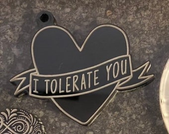 May include: Black enamel heart-shaped pin with a white banner that reads "I tolerate you".