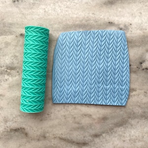May include: A set of two blue and green silicone rolling pins with a textured pattern. The rolling pins are used for creating decorative patterns on fondant or clay.