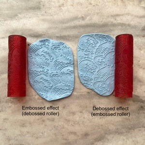 Pode incluir: Dois rolos vermelhos com um padrão de ondas. Um rolo é usado para criar um efeito em relevo em uma superfície azul claro, enquanto o outro cria um efeito em baixo relevo. O texto "Embossed effect (debossed roller)" está abaixo da superfície em relevo, e o texto "Debossed effect (embossed roller)" está abaixo da superfície em baixo relevo.