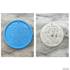 Könnte beinhalten: Ein runder blauer und weißer Anhänger mit einer Grafik einer maskierten Figur, die ein Messer hält, und dem Text "Slashing Through The Snow".