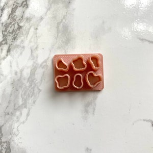 May include: A pink silicone mould with six different shaped cavities. The mould is designed for making small resin crafts.