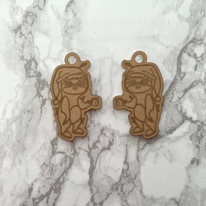 May include: Two brown wooden ornaments shaped like sloths wearing Santa hats and holding mugs. The ornaments are laser cut and have a rustic look.